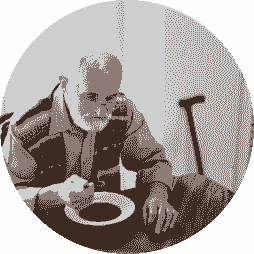 An elderly man with a beard sits at a table, eating soup from a bowl with a spoon. A walking cane rests against the wall beside him. The sepia-toned image, displayed in a circular frame, reflects themes supported by the Nanaimo Brain Injury Society.